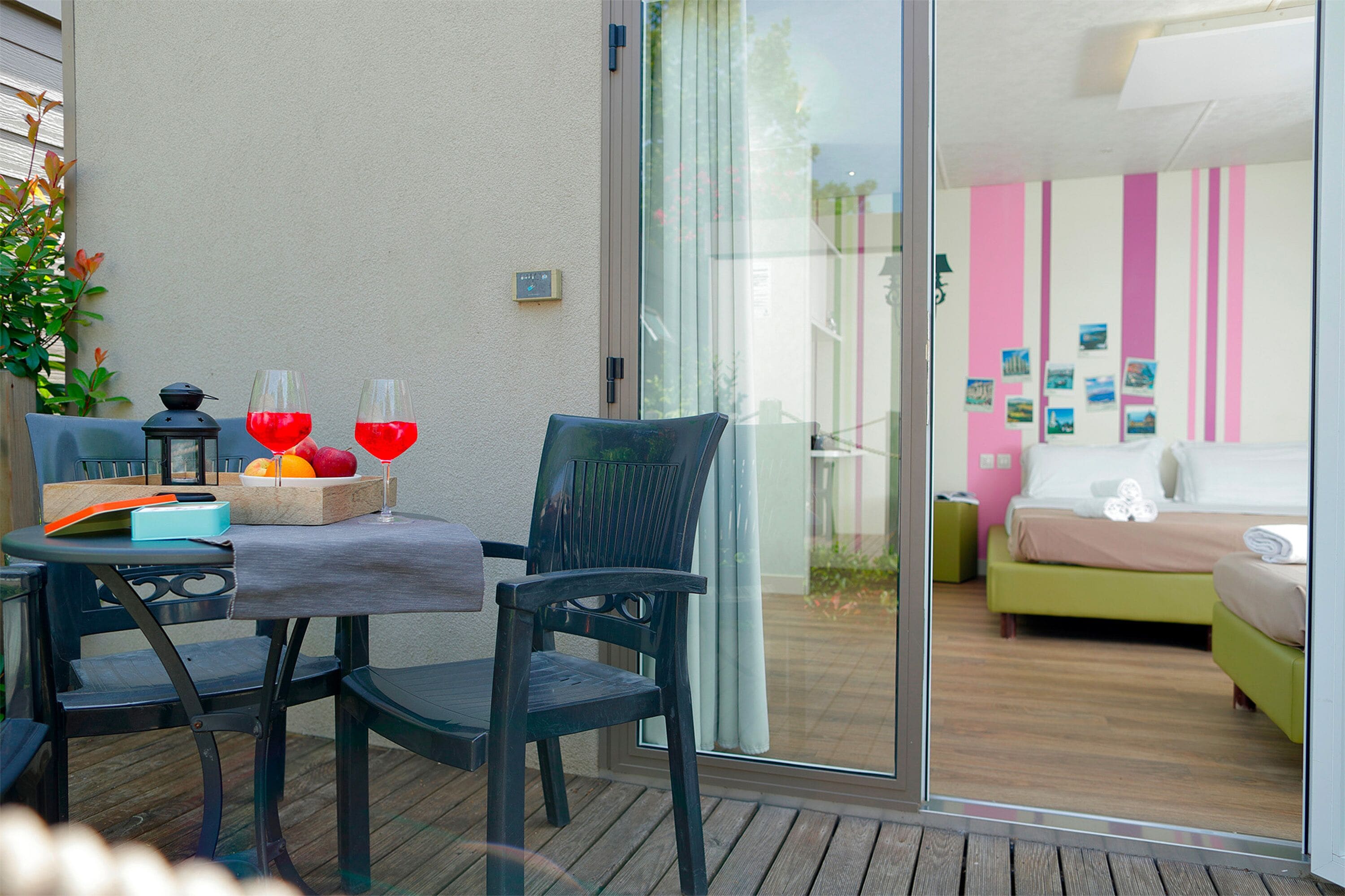A balcony with a table set for two, a chair, a lantern, and a book.