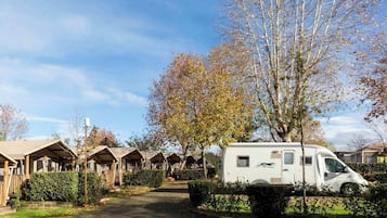 A row of wooden cabins with a white RV parked in front.
