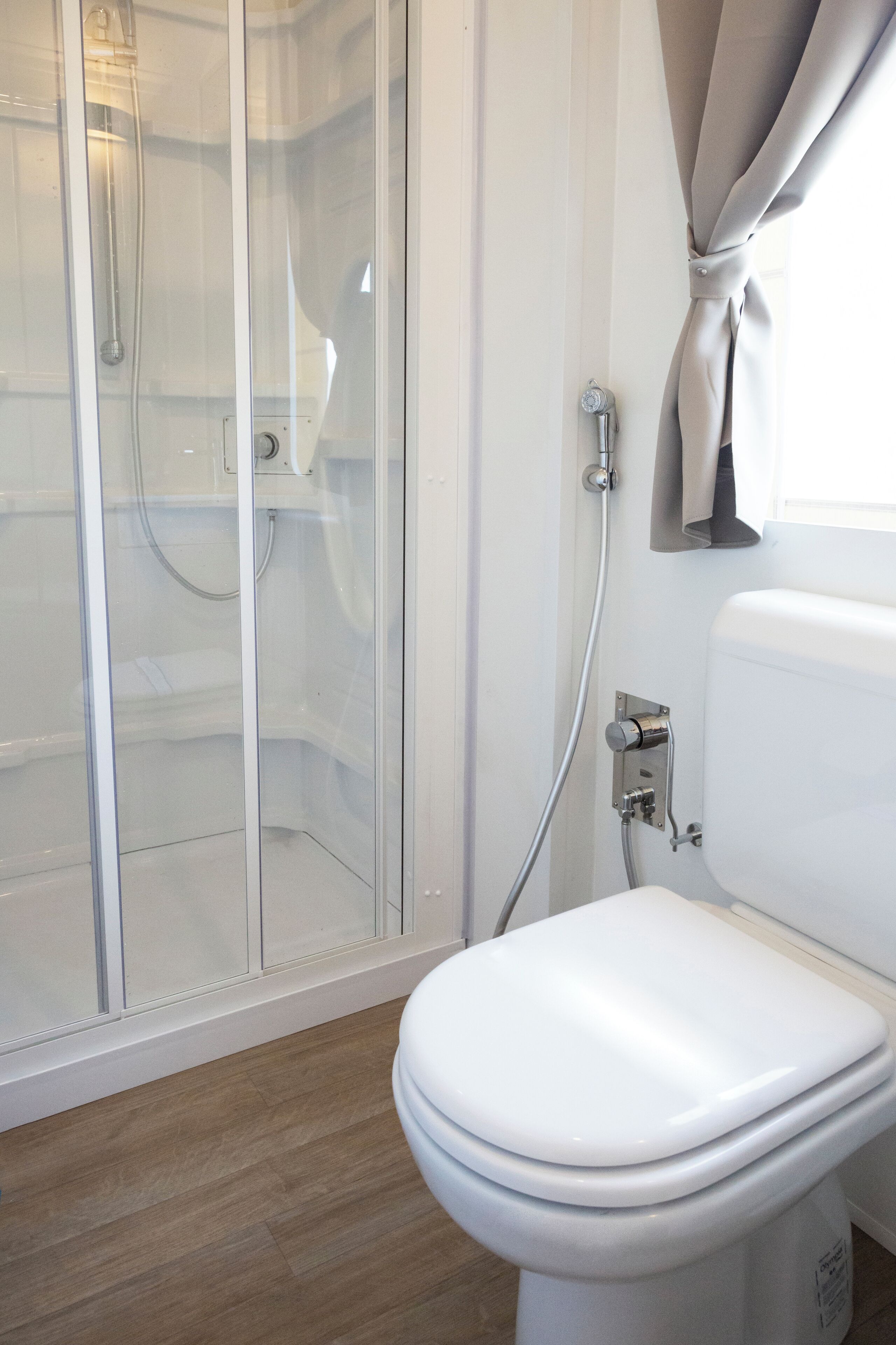 A modern bathroom with a glass-enclosed shower, a white toilet, and a towel rack.