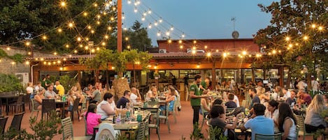An outdoor dining area with string lights, tables, and chairs.