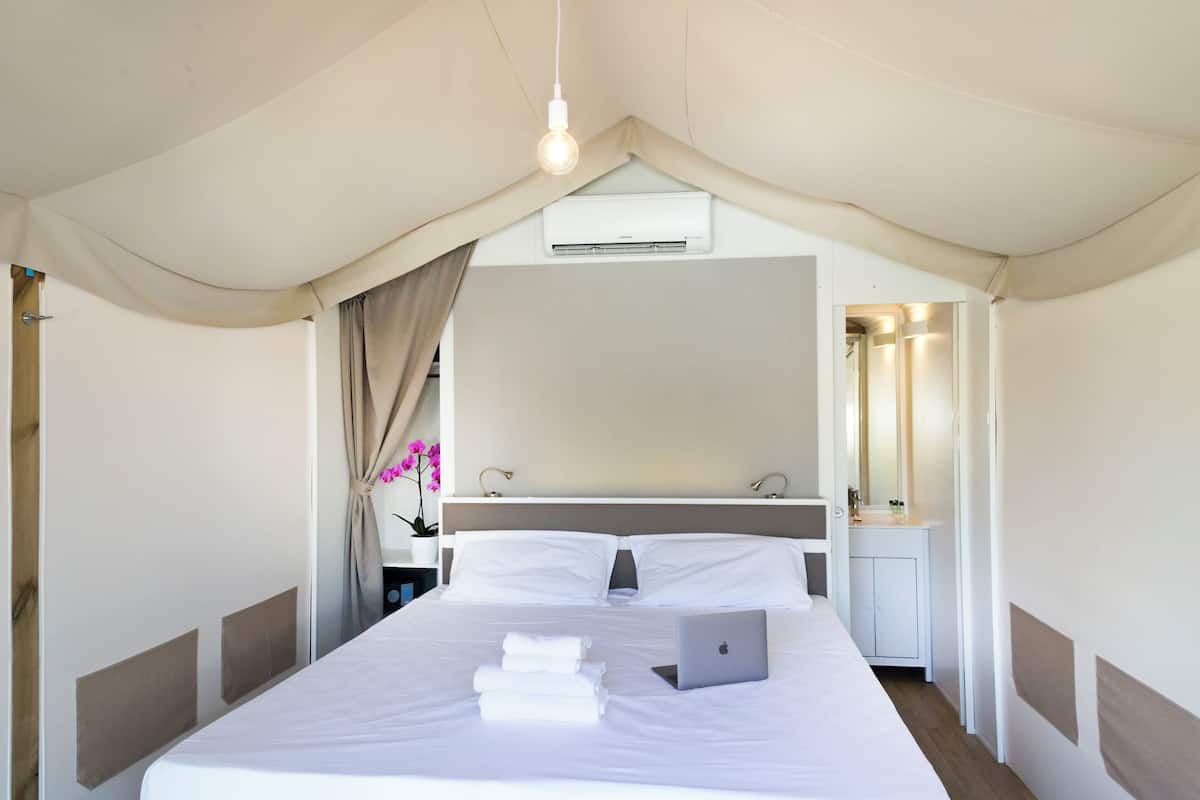 Moderni hotellihuone, jossa on sänky, kannettava tietokone ja kylpyhuone, jossa on peili.