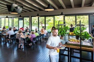 Ein Restaurant mit großen Fenstern, Holzböden und einer Buffettheke mit Obst und Gemüse.