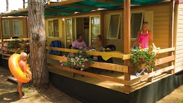 Een houten chalet met terras, buitenmeubels en plantenpotten.