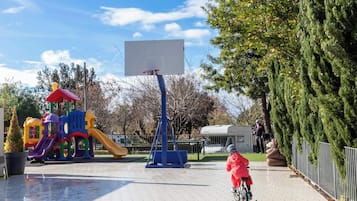 Un parque infantil con un aro de baloncesto, un tobogán y una estructura de juegos.