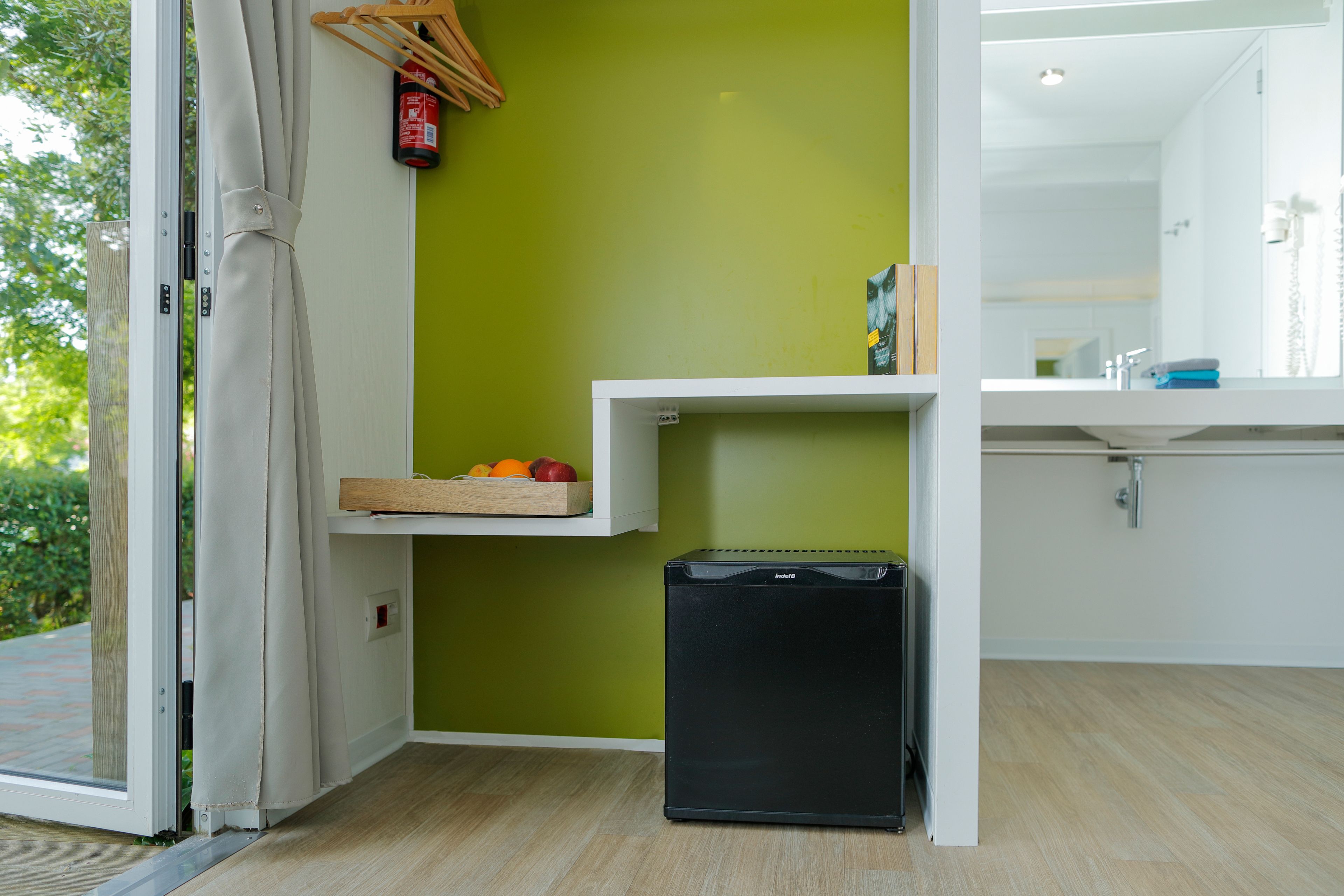 A compact kitchen with a green wall, a small countertop, and a black refrigerator.