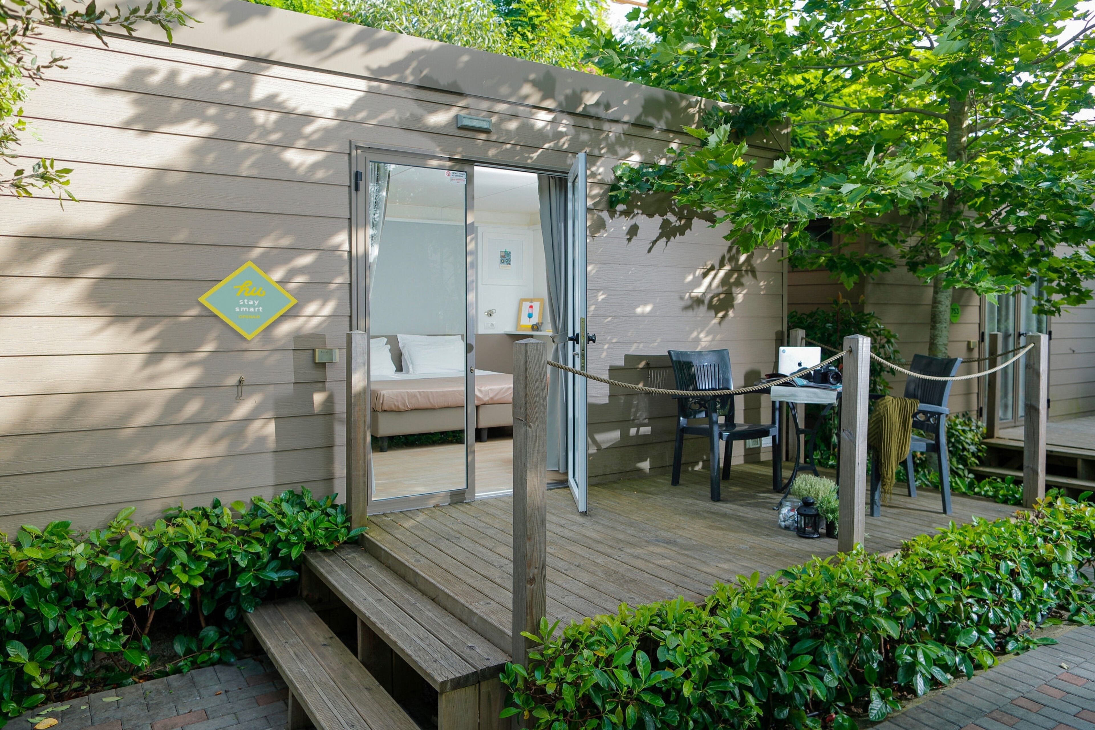 A wooden deck with a sofa and chairs, a small table, and a rope barrier.