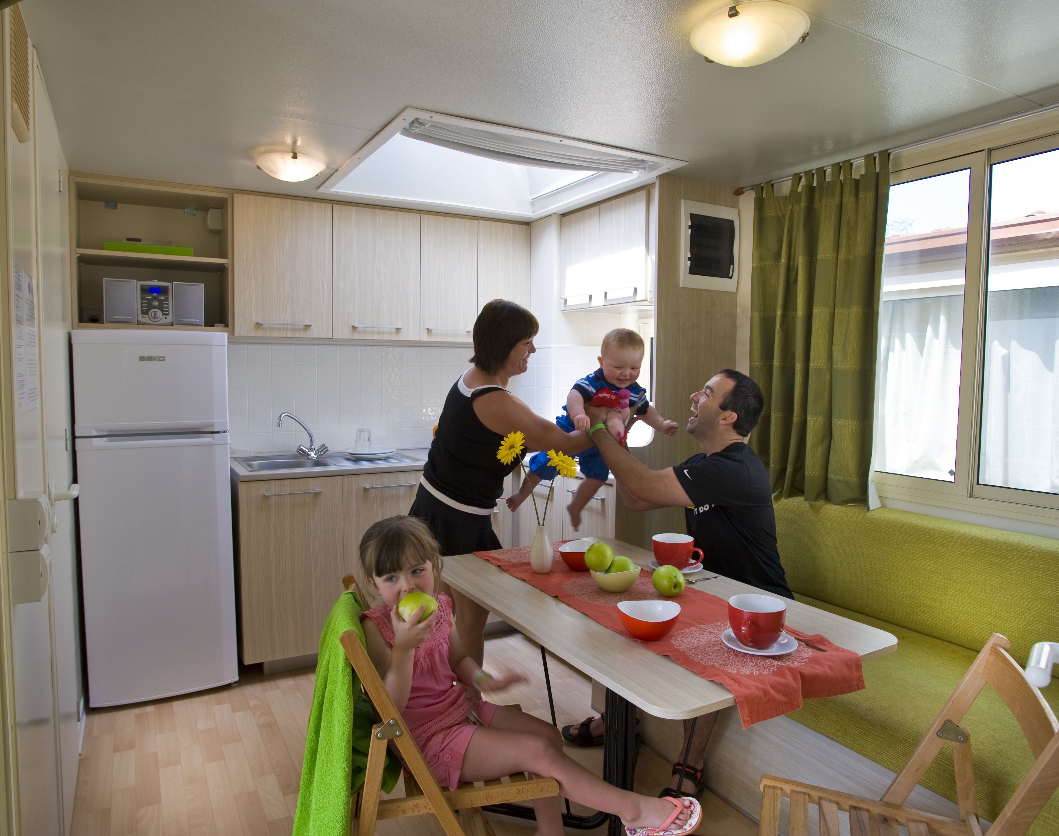A compact kitchen with a refrigerator, sink, and a dining area with a table set for four.