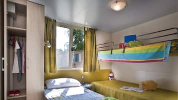 Habitación tipo dormitorio con literas, un armario y una ventana con cortinas.