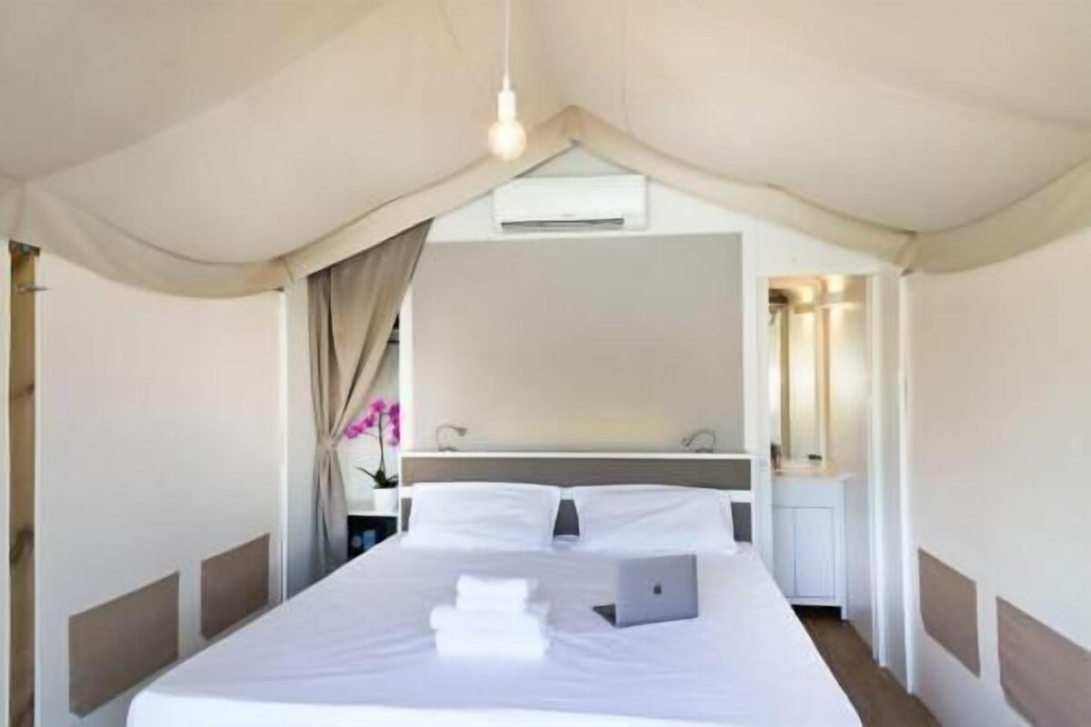 Habitación de hotel con cama, escritorio, silla, espejo y ventana con cortinas.