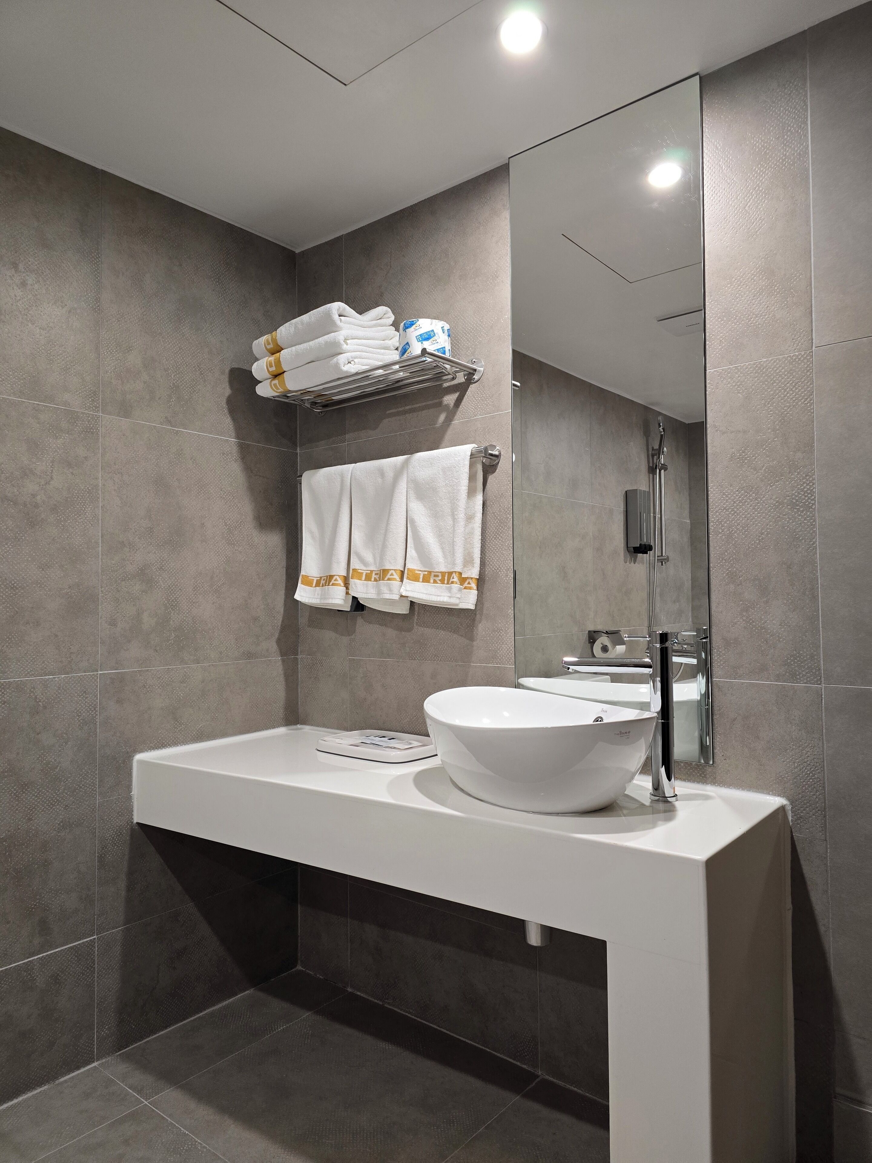 A modern bathroom with a white vanity, a large mirror, and a towel rack with folded towels.