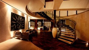 A spacious lobby with a curved staircase, comfortable seating, and a large abstract artwork on the wall. - The Riverside Hotel (Seoul)