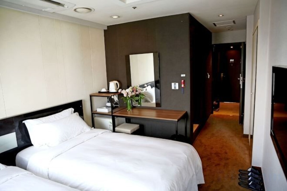 Una camera d'albergo con un letto, una scrivania, una sedia, uno specchio e una televisione.
