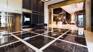 A modern lobby with a black and white tiled floor, a reception desk, and a seating area. - The Riverside Hotel (Seoul)