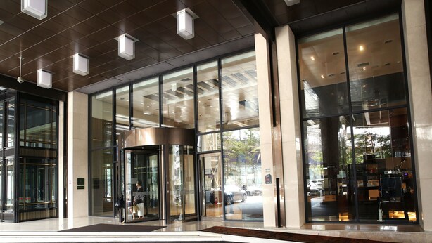 A modern hotel entrance with glass doors, a revolving door, and a visible street view. - The Riverside Hotel (Seoul)