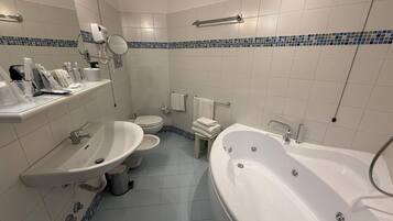 Un baño moderno con una bañera grande, un lavabo, un inodoro y un espejo.