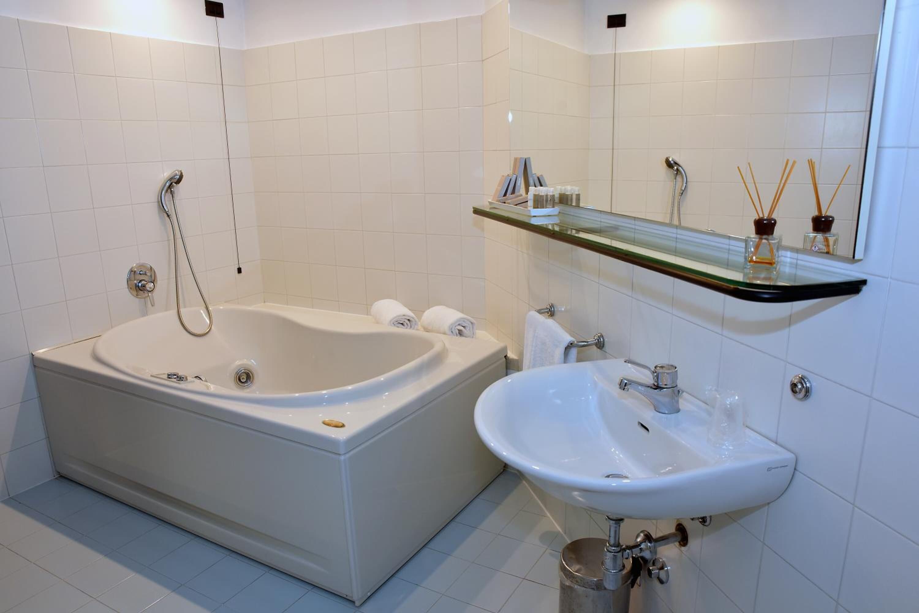A modern bathroom with a freestanding bathtub, a wall-mounted sink, and a glass shelf above the sink.