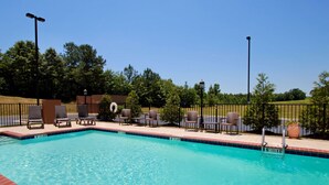 Una piscina con sillas de descanso y una cerca.