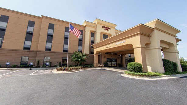 A hotel entrance with a flag, signage, and a clear sky.