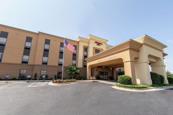 A hotel entrance with a flag, signage, and a clear sky.