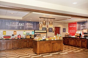 A breakfast bar with a checkered floor, wooden cabinets, and hanging pendant lights.