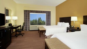 Habitación de hotel con dos camas, un escritorio con silla, televisión y ventana con cortinas.