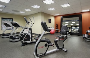 Un gimnasio con cintas de correr, elípticas, máquinas de remo y pesas sueltas.
