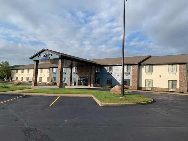 A hotel with a covered entrance, multiple rooms, and a parking lot.