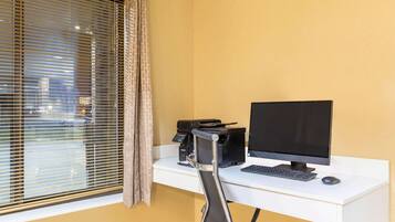 A workspace with a desk, computer, printer, and chair.