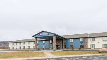 A multi-story hotel with a covered entrance, a parking lot, and a grassy area in front.