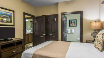 A hotel room with a bed, a television, a desk, a lamp, and a ceiling fan.