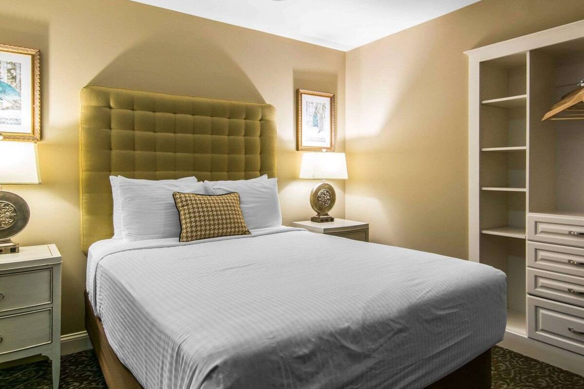 Una habitación de hotel con una cama grande, un armario y un ventilador de techo.