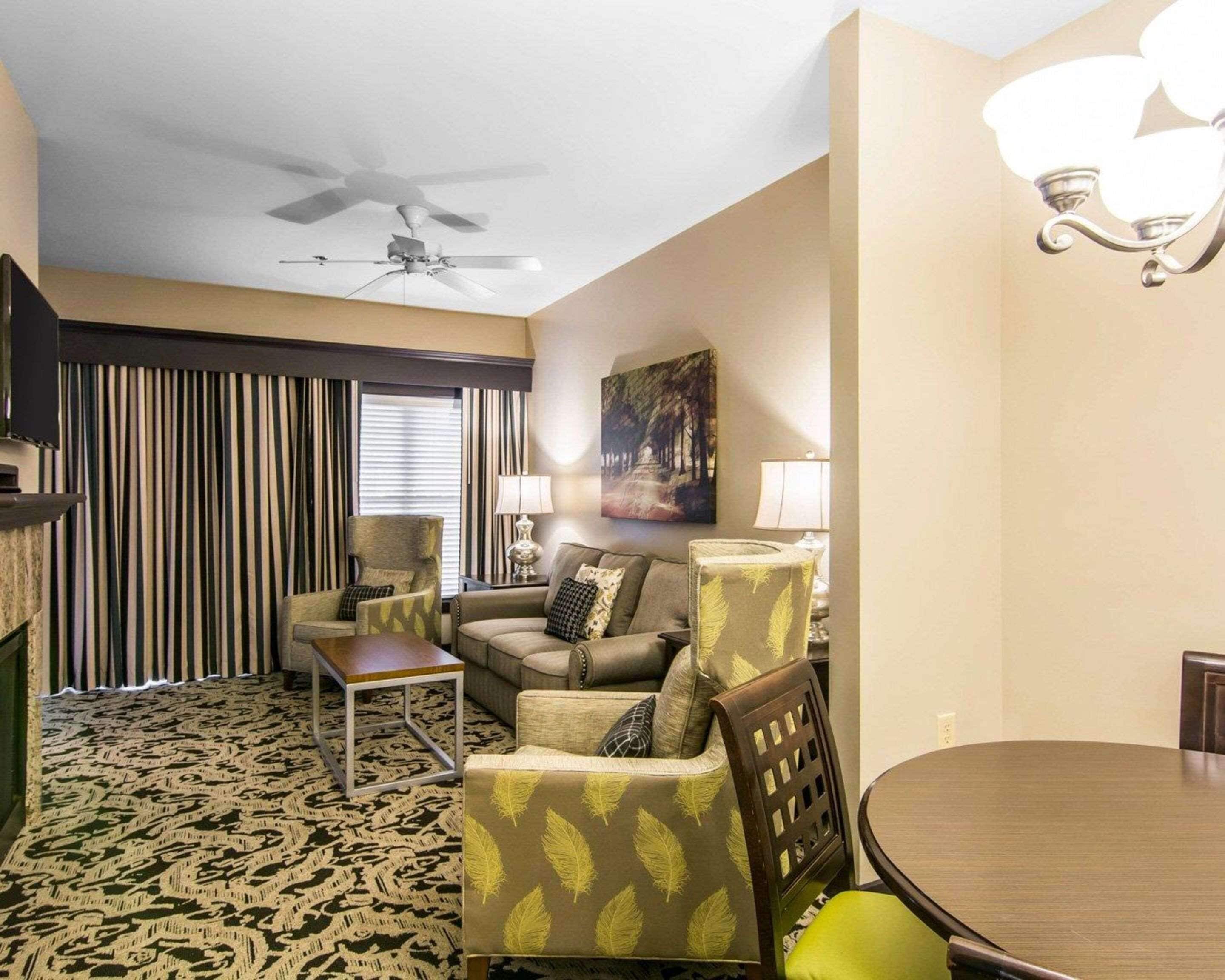 A living room with a ceiling fan, striped curtains, a painting, and a dining table.