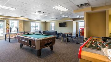 Une salle de loisirs équipée d’une table de billard, d’un baby-foot et d’un espace détente avec des sièges.