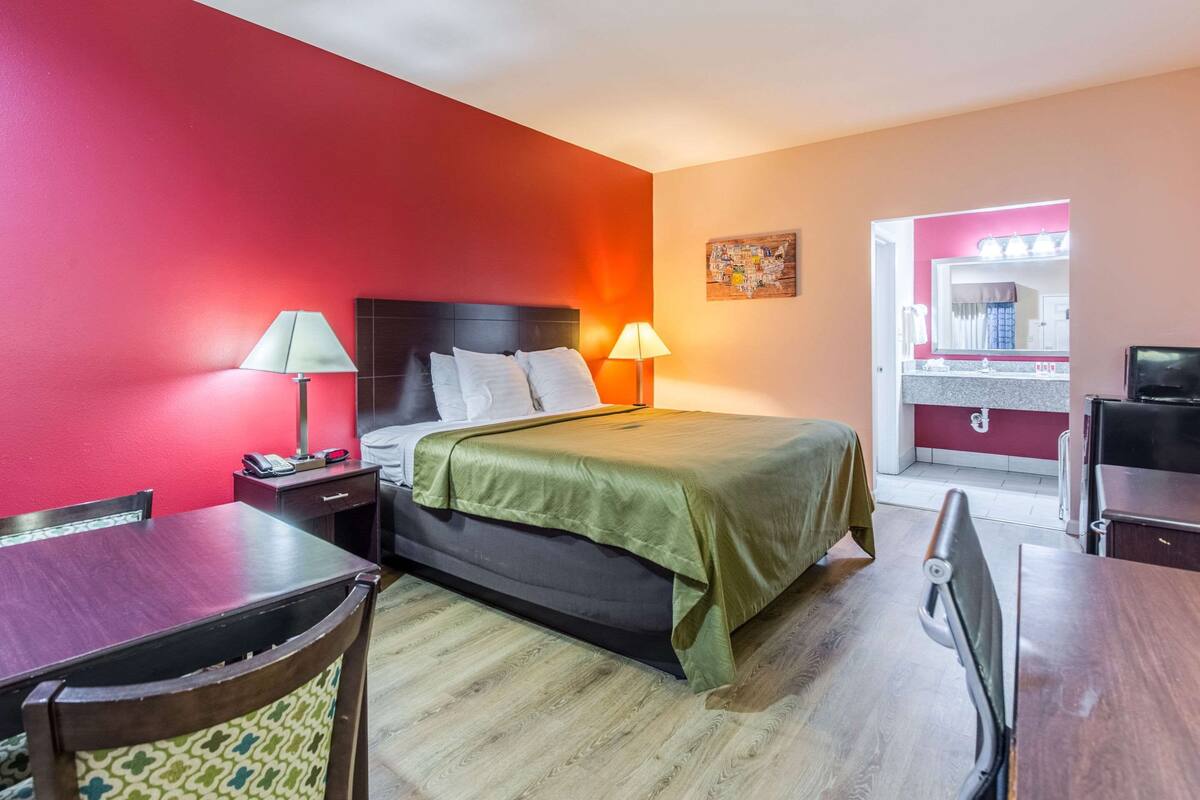 A hotel room with a bed, bedside lamps, a desk, and a chair.