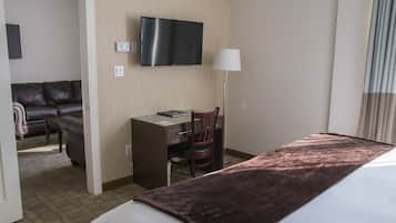 Une chambre d’hôtel avec un lit, un bureau, une chaise, une télévision et un canapé.