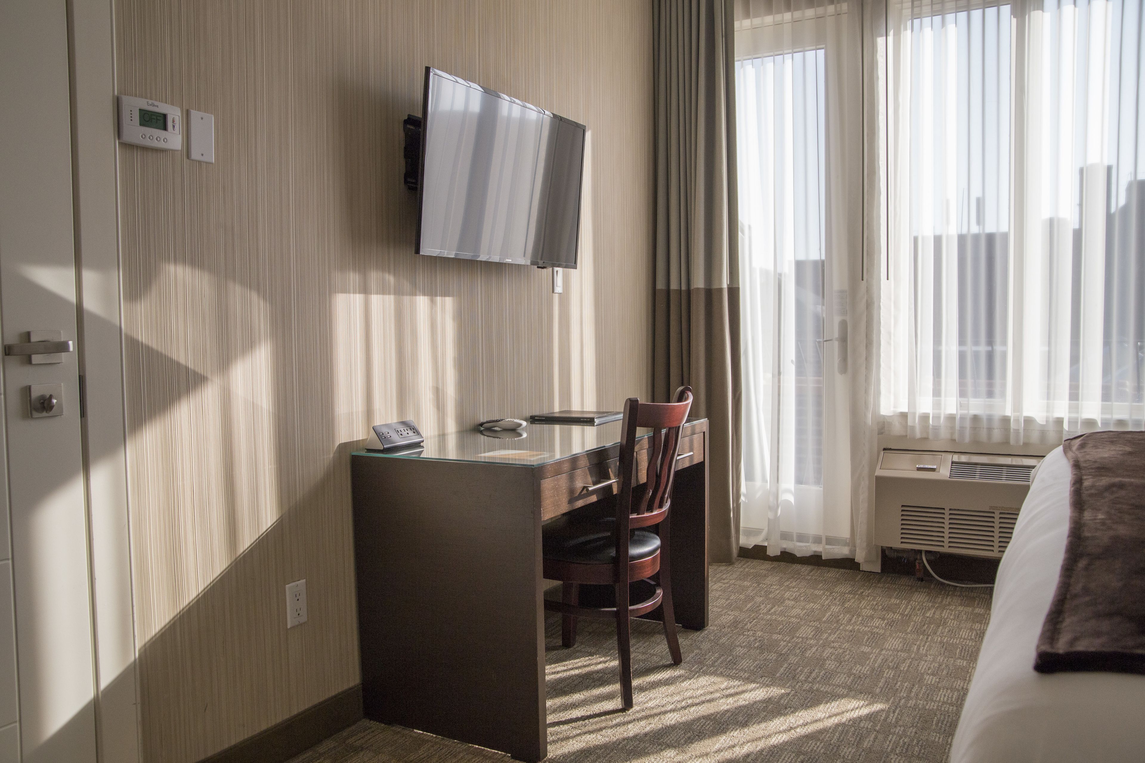 Una habitación de hotel con escritorio, silla, televisión y cama.