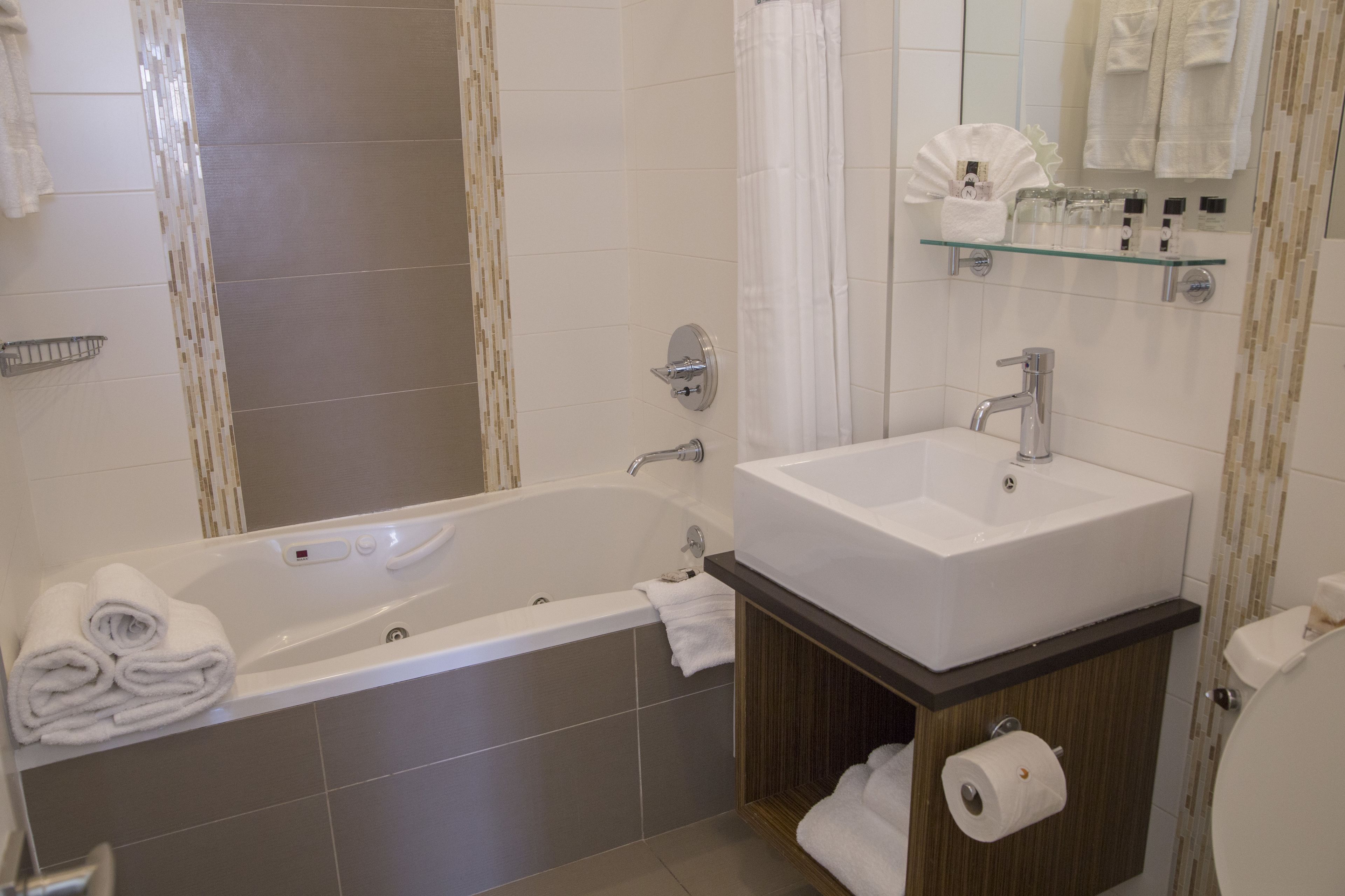 A modern bathroom with a bathtub, a sink, and a toilet. There are towels and toiletries visible.