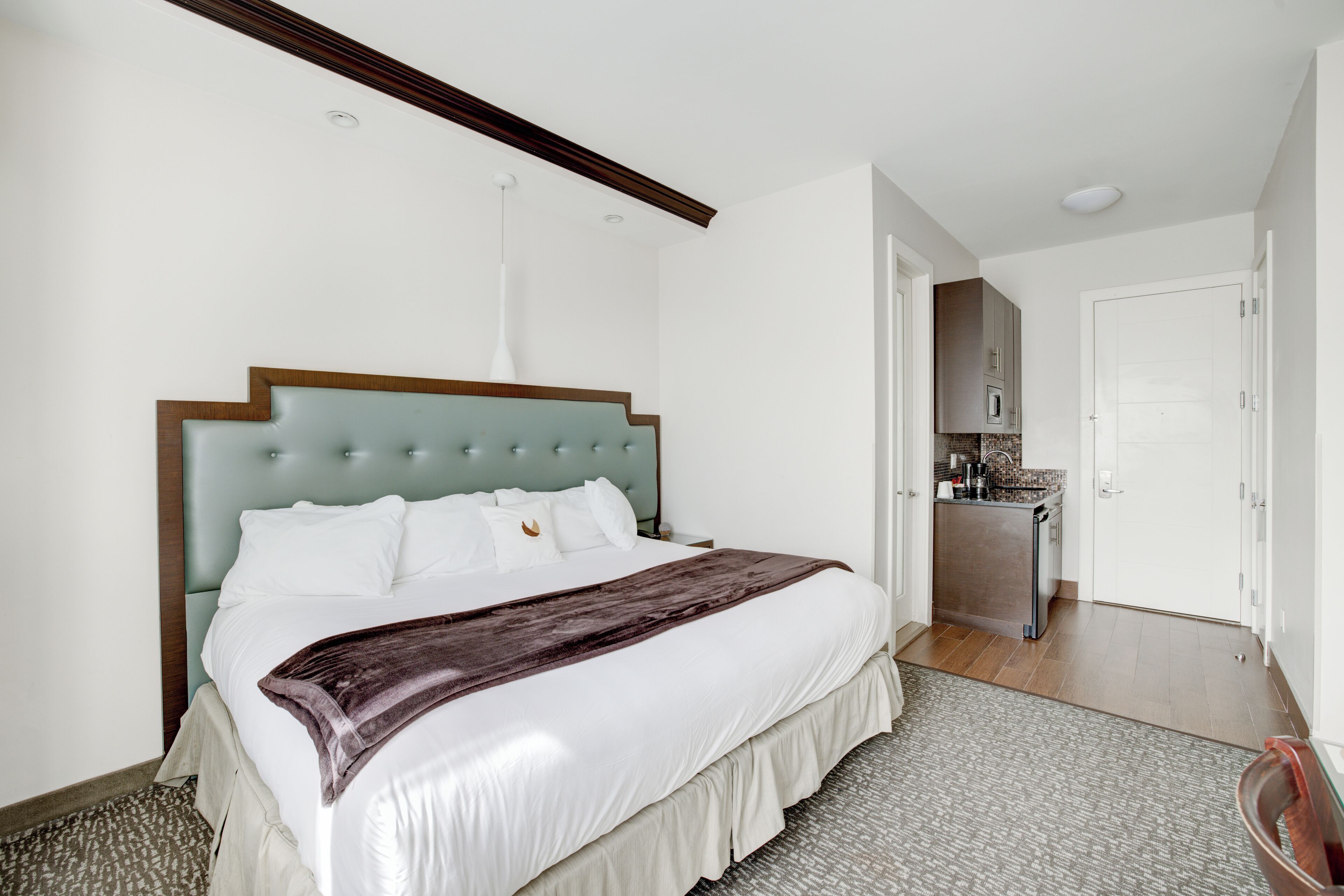 Une chambre d’hôtel moderne dotée d’un grand lit, d’un bureau intégré et d’une kitchenette.