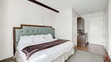 Une chambre d’hôtel moderne dotée d’un grand lit, d’un bureau intégré et d’une kitchenette.
