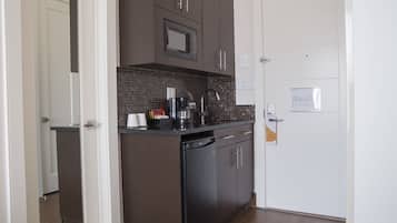 Una cocina compacta con armarios marrón oscuro, un lavavajillas negro y un salpicadero de azulejos.