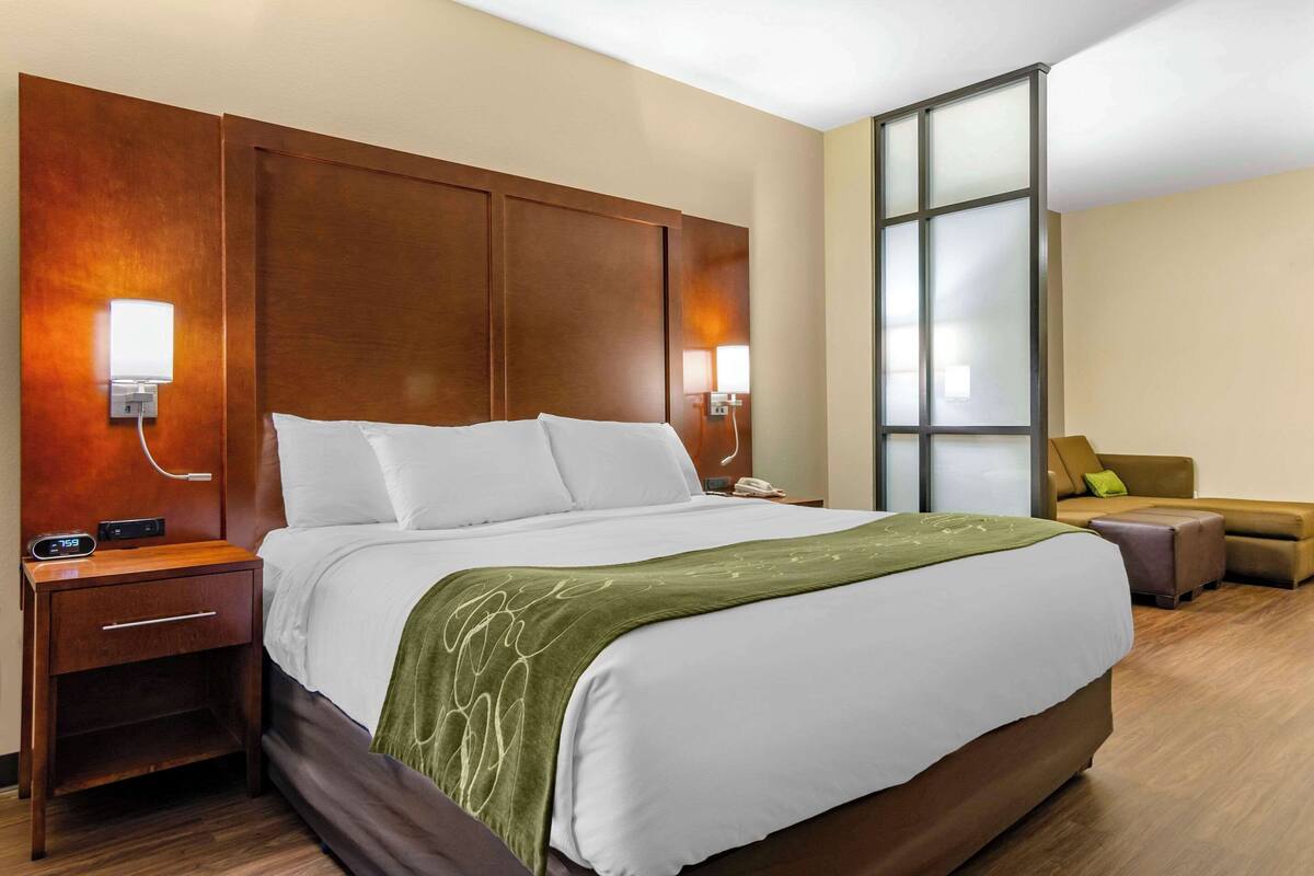 Ein Hotelzimmer mit einem großen Bett, Nachttischen, einer Sitzecke und einem großen Fenster.