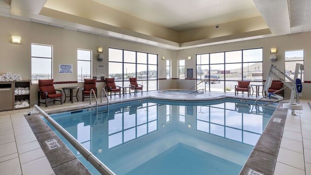 Ein Poolbereich mit freiem Blick auf den Himmel durch große Fenster, ein Pool mit Sicherheitsleiter und mehrere Liegestühle.