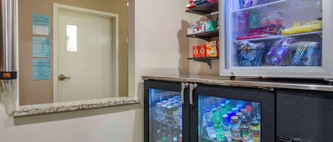 Ein Hotelzimmer mit Minibar, einem mit Getränken gefüllten Kühlschrank und einer Tür mit Lichtschalter.