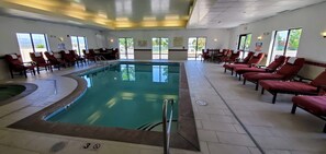 Zona de piscina con sillas reclinables rojas, mesa de billar y un cartel que indica que no hay socorrista de servicio.