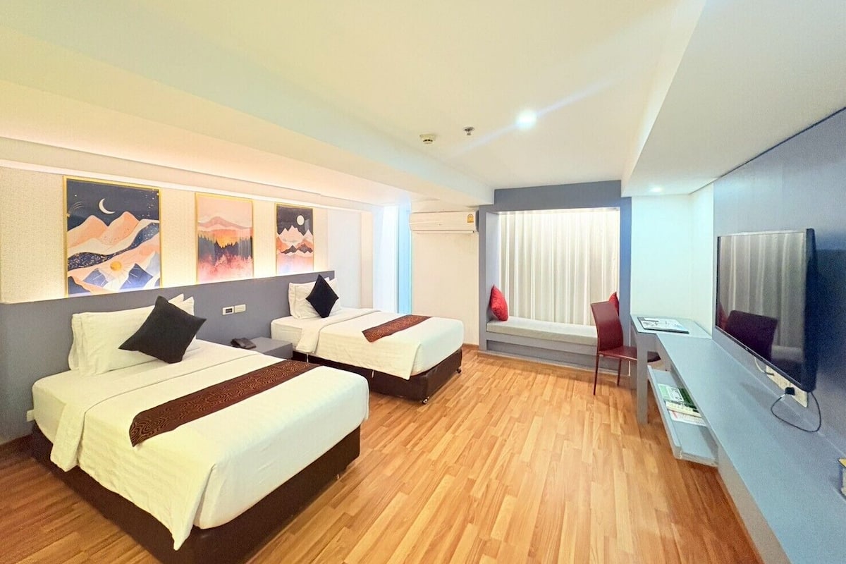 A hotel room with two beds, a TV, and artwork on the wall.