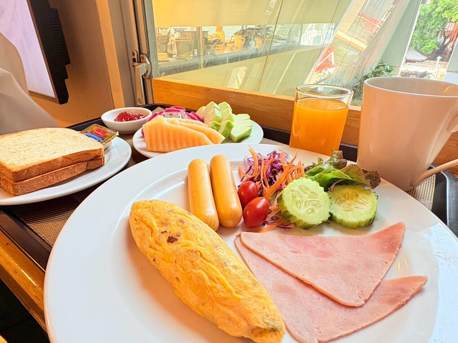 A breakfast plate with toast, ham, eggs, and vegetables.