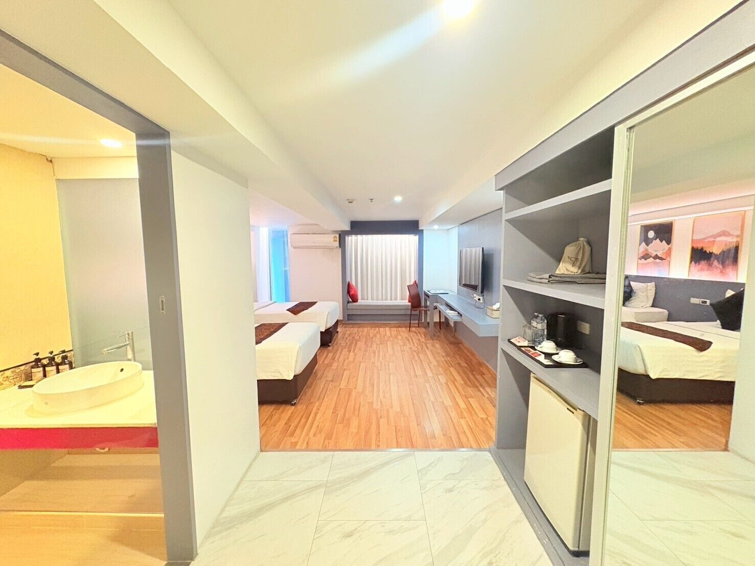 A hotel room with two beds, a bathroom with a bathtub, a desk with a chair, and a TV.