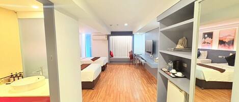 A hotel room with two beds, a bathroom with a bathtub, a desk with a chair, and a TV.