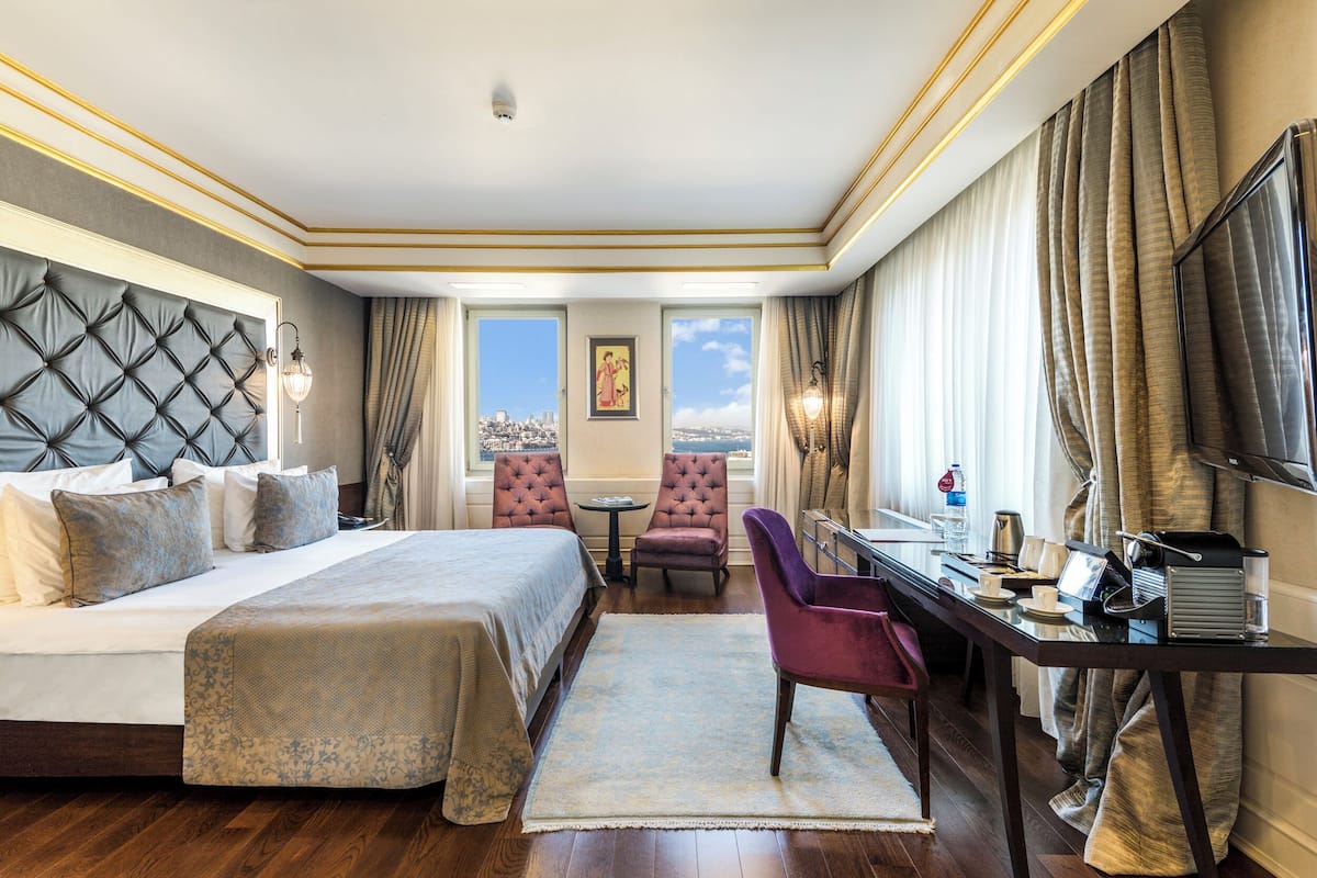 Une chambre d’hôtel avec un grand lit, un bureau, une chaise et une vue sur la ville.
