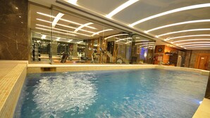 An indoor swimming pool with a glass wall, exercise equipment, and modern lighting. - Levni Hotel & Spa - Special Class (Istanbul)